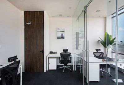 Brightly lit workspace with white desks, ergonomic chairs, and glass partition walls.