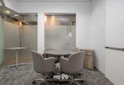 Small meeting room with a round table and grey upholstered chairs.