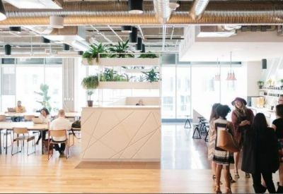 Bright open-plan workspace with a central white divider and groups of people collaborating.
