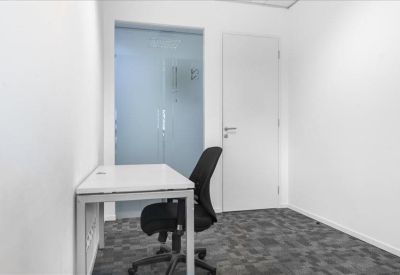 Minimalist private office suite with a white desk and frosted glass door.