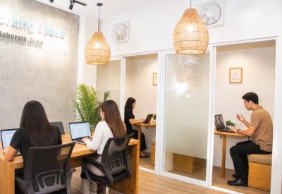 Modern office space featuring individual glass-partitioned workstations and wooden desks.
