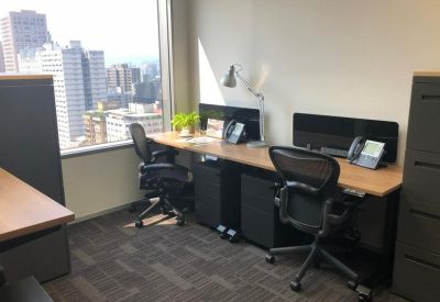Bright two-person office suite featuring wood-topped desks and large windows with city views.
