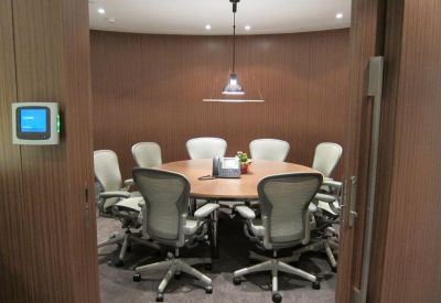 Circular meeting room with wood-paneled walls and modern ergonomic chairs around a round table.