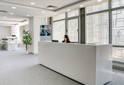 Minimalist white reception desk staffed by a professional receptionist near large windows.