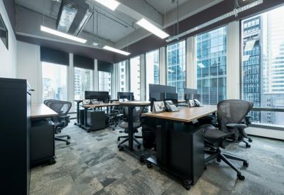 Bright open-plan office space with height-adjustable desks and expansive window views.