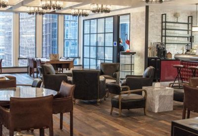 Modern lounge area featuring diverse seating options, a coffee bar, and large windows with city views.