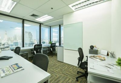 Bright multi-person office space with individual workstations and a whiteboard.
