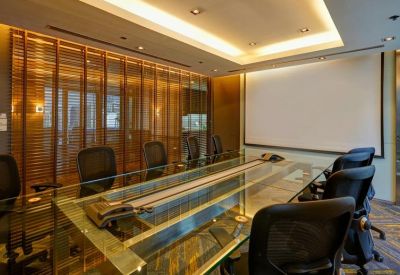 Modern conference room featuring a long glass table and a large projector screen.