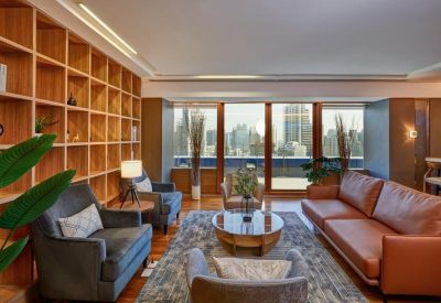 Elegant lounge area with leather and velvet seating, bookshelves, and large windows.