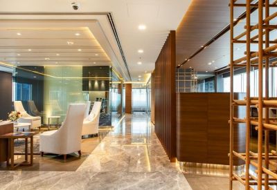 Modern lobby area with polished stone floors, warm wood accents, and white designer armchairs.