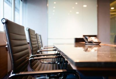 Close-up of a professional conference table with leather chairs and a white backdrop.