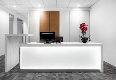 Minimalist reception area with a glowing white desk and red flower arrangement.