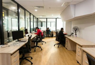 Bright open-plan office with wooden desks and glass partitions.