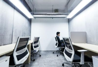 Bright open-plan office featuring ergonomic chairs and long shared workstations.