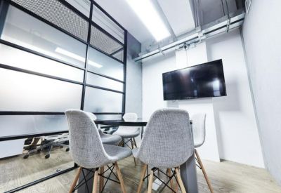 Professional meeting room with a wall-mounted TV and grey modern chairs.