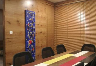 Modern meeting room featuring wooden wall paneling and a vertical blue abstract art piece.