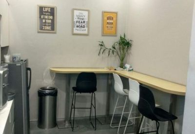 Modern office pantry with high-top seating, wall art, and a refrigerator.