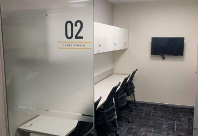 Semi-private office studio featuring a long white desk and black ergonomic chairs.