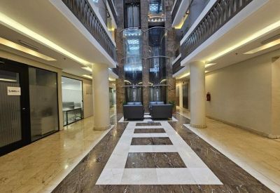 Spacious building lobby with polished floors, marble accents, and glass elevators.