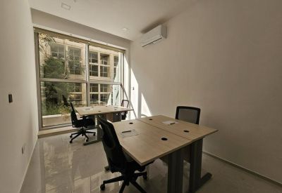 Bright two-person office suite with light wood desks and large windows.