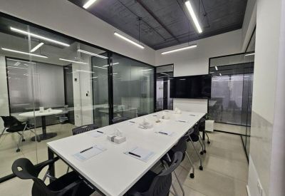 Professional meeting room with a white table, black chairs, and glass partitions.