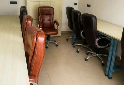 Private office space with wooden desks and ergonomic brown leather chairs.