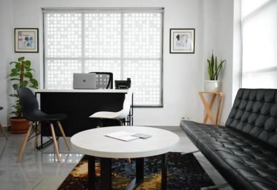 Brightly lit breakout area with a round white table, comfortable sofa, and potted plants.