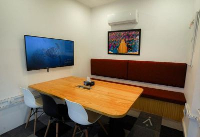 Casual meeting room with a wooden table, built-in bench seating, and a wall-mounted TV.