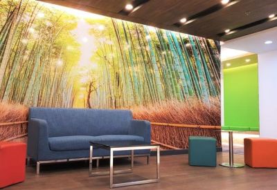 Lounge area featuring a nature-themed wall mural, blue seating, and colorful ottoman stools.
