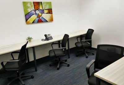 Private office space with a long white desk, mesh chairs, and abstract colorful artwork.