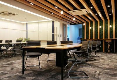 Spacious boardroom with a long wooden table, black leather chairs, and a slatted timber ceiling.