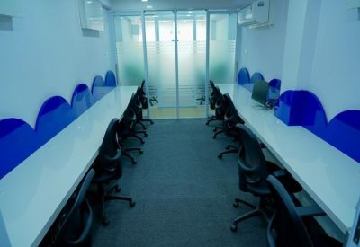 Tidy four-person desk pod with blue privacy dividers and white desks.