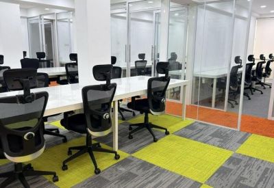 Open-plan workspace with white desks and black ergonomic chairs on yellow checkered carpet.