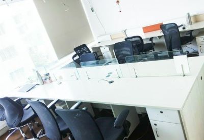 Shared workspace area with long white desks and rows of black office chairs.