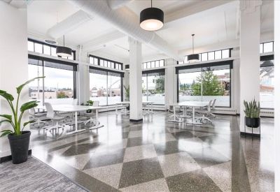 Spacious communal coworking area with patterned flooring and potted plants.