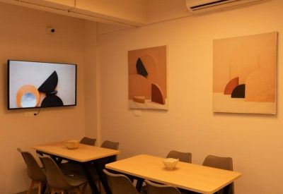 Communal breakout area with wooden dining tables, modern chairs, and colorful wall art.