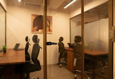Private glass-walled office with wooden desks and ergonomic chairs.