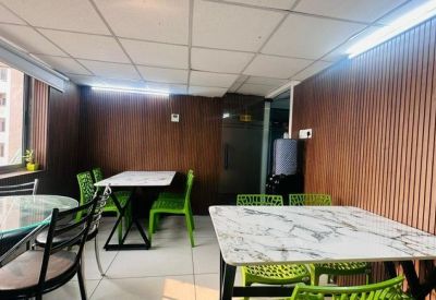 Communal dining or breakout area with white marble-topped tables and bright green chairs.