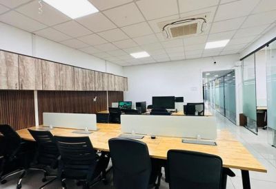 Bright open-plan workspace with wooden desks, ergonomic chairs, and glass partitions.