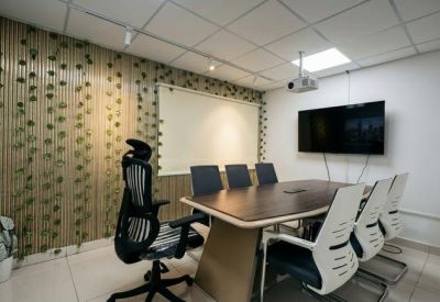 Modern meeting room with a large screen, dark table, and a decorative vine wall.