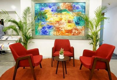 Lounge area with red armchairs and a large colorful abstract painting.
