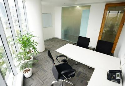 Private corner office suite with an L-shaped white desk and green plants.