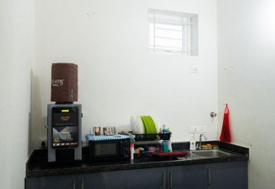 Compact office kitchen with coffee machine, microwave, and sink area.