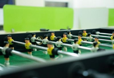 Close-up of a foosball table with yellow and blue players in a break room.