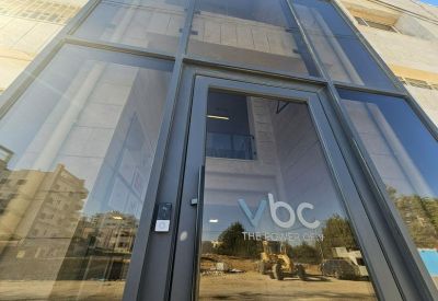 Exterior entrance of the Vbc Dead Sea Road building with glass facade.