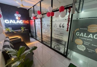 Branded reception area with a dark desk, soft seating, and festive balloon decorations.