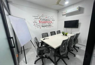 Professional meeting room with a white table, black chairs, and motivational wall graphics.