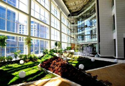 Spacious sun-drenched atrium with indoor landscaping and floor-to-ceiling windows.