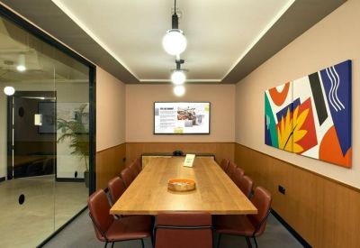 Contemporary meeting room with a wooden table, red chairs, and vibrant abstract wall art.