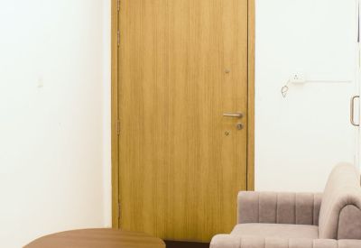 Waiting area featuring a plush grey sofa, wooden coffee table, and light wood door.